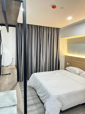 a bedroom with a large white bed and curtains at EpochHotel in Taiping
