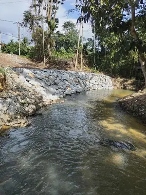 a river with a stone wall next to a river at Z&S Gerik Hillview Homestay in Gerik