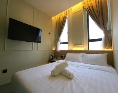 a white stuffed animal laying on a bed with a television at Georgetown AY Hotel in George Town