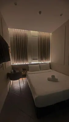 a bedroom with a bed and a chair in front of a window at Georgetown AY Hotel in George Town