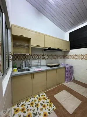 a kitchen with wooden cabinets and a kitchen rug at Ruzarani Home Meru Suria in Chemor