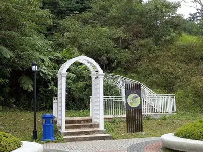 a white arch with stairs and a sign in a park at 1BR Cool Homestay at Cameron Golden Hills Night Market in Brinchang