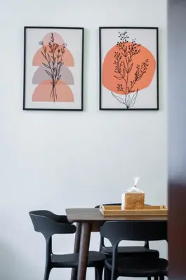 three framed prints of flowers on a wall with a table and chairs at Aayu Beach St - George Town Penang in George Town