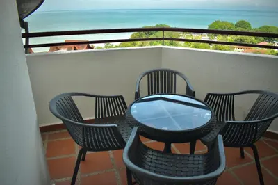 a table and chairs on a balcony with a view of the ocean at Seaview - Sri Sayang in Batu Ferringhi