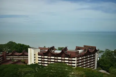 a large building with the ocean in the background at Seaview - Sri Sayang in Batu Ferringhi