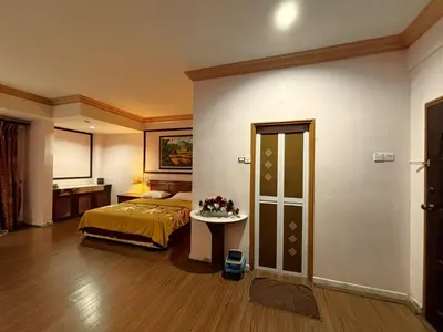 a bedroom with a bed and a table in a room at Cool Point Hotel in Tanah Rata