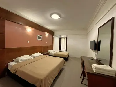 a hotel room with two beds and a mirror at Cool Point Hotel in Tanah Rata