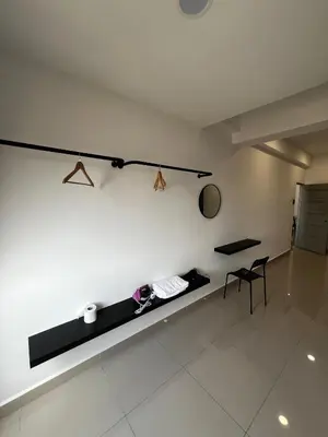 a room with a white wall with a bench and a chair at Stay in Passionate in Sitiawan