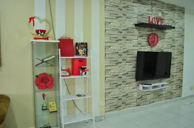 a living room with a tv on a stone wall at Uwais Homestay Segari Lumut in Lumut
