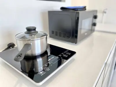 a pot sitting on top of a counter next to a microwave at Urban Suites #Creamy style #Infinity Pool #local neighbourhood #5pax #3BR 2bath #2Queen 1Single #Quality well maintained #Private host in Jelutong
