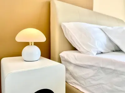 a white lamp on a nightstand next to a bed at Urban Suites #Creamy style #Infinity Pool #local neighbourhood #5pax #3BR 2bath #2Queen 1Single #Quality well maintained #Private host in Jelutong