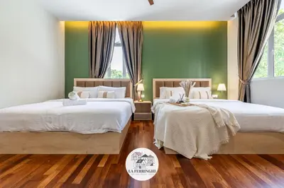 two beds in a bedroom with green walls and wood floors at La Ferringhi Villa in Batu Ferringhi