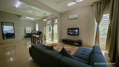 a living room with a blue couch and a tv at Homestay Qasrina Semi D 4 Bilik in Kepala Batas