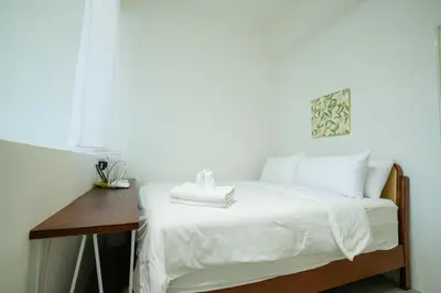 a bedroom with a bed with white sheets and a wooden desk at Bunny's Warm Penthouse by Comfy Sofy in Brinchang
