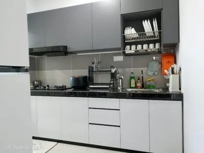 a kitchen with white cabinets and black counter tops at NuTiQa Homestay Meru Ipoh Perak in Ipoh