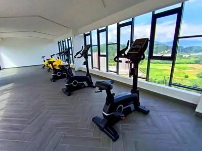 a gym with treadmills and bikes in a room with windows at The Horizon Ipoh Dual L13A by Grab A Stay in Ipoh