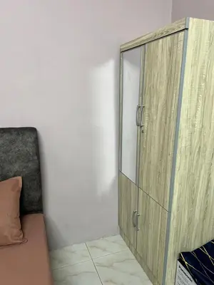 a glass cabinet in a room with a couch at Faza Homestay Meru Ipoh in Ipoh