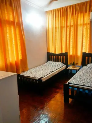 two beds in a room with orange curtains at Cozy & Comfy 3 rooms apartment near beach in Batu Ferringhi