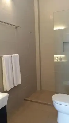 a bathroom with a toilet and a shower with towels at Beach Front Bungalow Tanjung Bungah in George Town