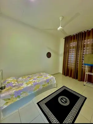 a bedroom with a bed and a rug on the floor at Aura Homestay in Sungai Petani