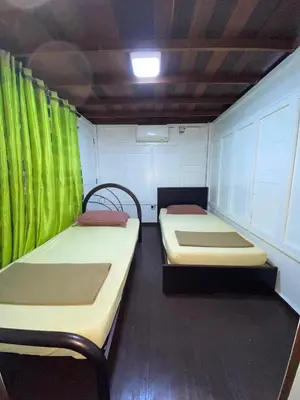 two beds in a room with green curtains at Nami Homestay Teluk Batik in Lumut