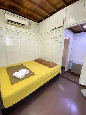 a small room with a yellow bed in it at Nami Homestay Teluk Batik in Lumut