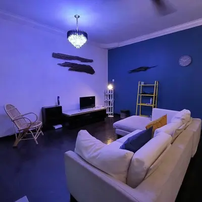 a living room with a white couch and a blue wall at Getaway Hometsay Neaby Beach batu Ferringghi 4BR for 15px in Tanjung Bungah