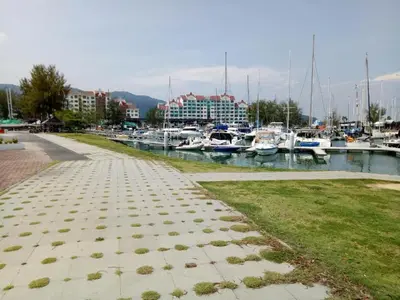 a walkway next to a marina with boats in the water at A sweet home for your trip in Lumut