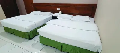 three beds in a hotel room with white sheets at Kampar Times Inn Hotel in Kampar