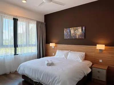 a bedroom with a large white bed with two lamps at Sunway Onsen Suite Cozy Homestay in Ipoh