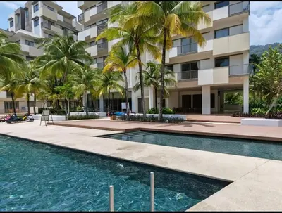 a swimming pool in front of a building with palm trees at By The Sea Beach Front and Seaview Apartment 2 in Batu Ferringhi