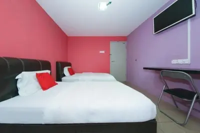 a bedroom with a large bed with a red wall at The Inn Hotel in Teluk Intan