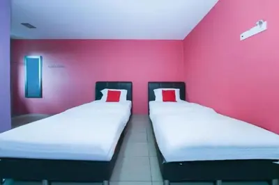 two beds in a room with a pink wall at The Inn Hotel in Teluk Intan
