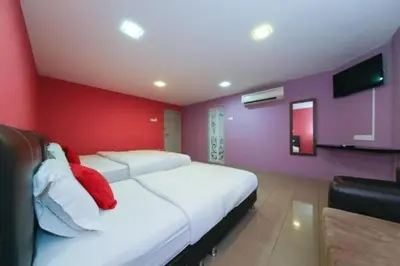 a bedroom with two white beds and a red wall at The Inn Hotel in Teluk Intan