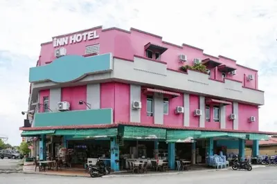a pink building with tables in front of it at The Inn Hotel in Teluk Intan