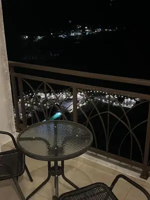 a glass table and chairs on a balcony at night at Nova \u5bb6\u5ead\u623f in Brinchang