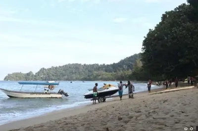 a group of people standing on a beach with a boat at 39 Lot 10 Pangkor Leisure Beach Studio in Pangkor