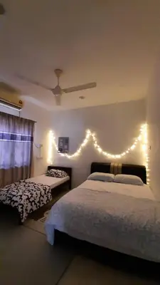 a bedroom with two beds and lights on the wall at Cozy House in Taiping in Taiping