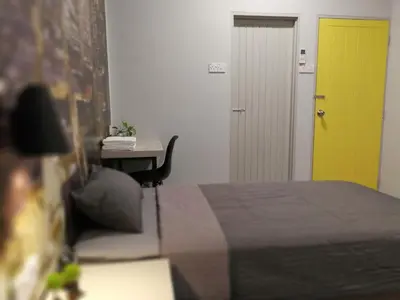 a bedroom with a bed and a yellow door and a desk at Check-Inn Guesthouse in Ipoh