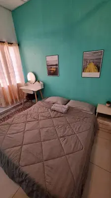 a bedroom with a large bed and a blue wall at MAR Homestay Seri Iskandar in Seri Iskandar