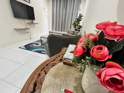 a living room with a vase of roses on a couch at Mama Zan Homestay in Seri Iskandar