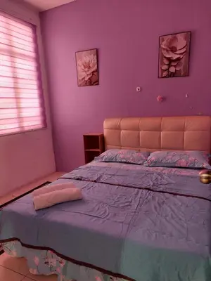a bedroom with a large bed with purple walls at Jerai Geopark Cottage Alamanda in Baling