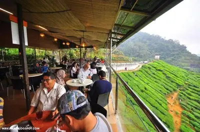 a group of people sitting at tables in a restaurant at Hillside cottage reflesia room in Tanah Rata