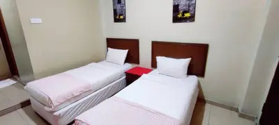 two beds in a small room with white sheets at De Clinique Hotel in Pangkor