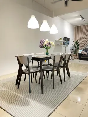 a dining room with a table and chairs on a rug at Zara Cozy Homestay in Seri Iskandar