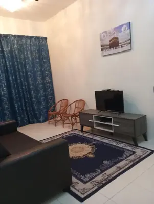 a living room with a couch and a tv at Lily Impiana Homestay in Baling