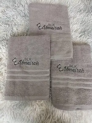 three towels on a blanket with the words bill and minnah at Bilik Umairah in Gerik