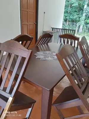 a dining room table with chairs and a wooden table with a cloth on it at Bilik Umairah in Gerik