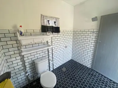 a white tiled bathroom with a toilet and a sink at Maison Helysa Homestay in Lumut
