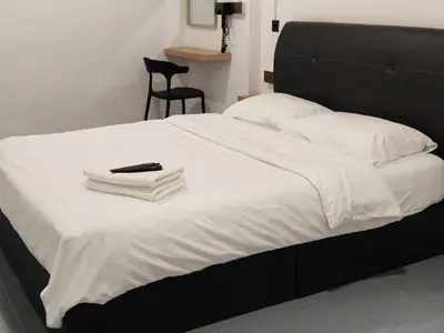 a white bed with a remote control on top of it at 23 Inn Queenbed Standard Room in Bukit Mertajam